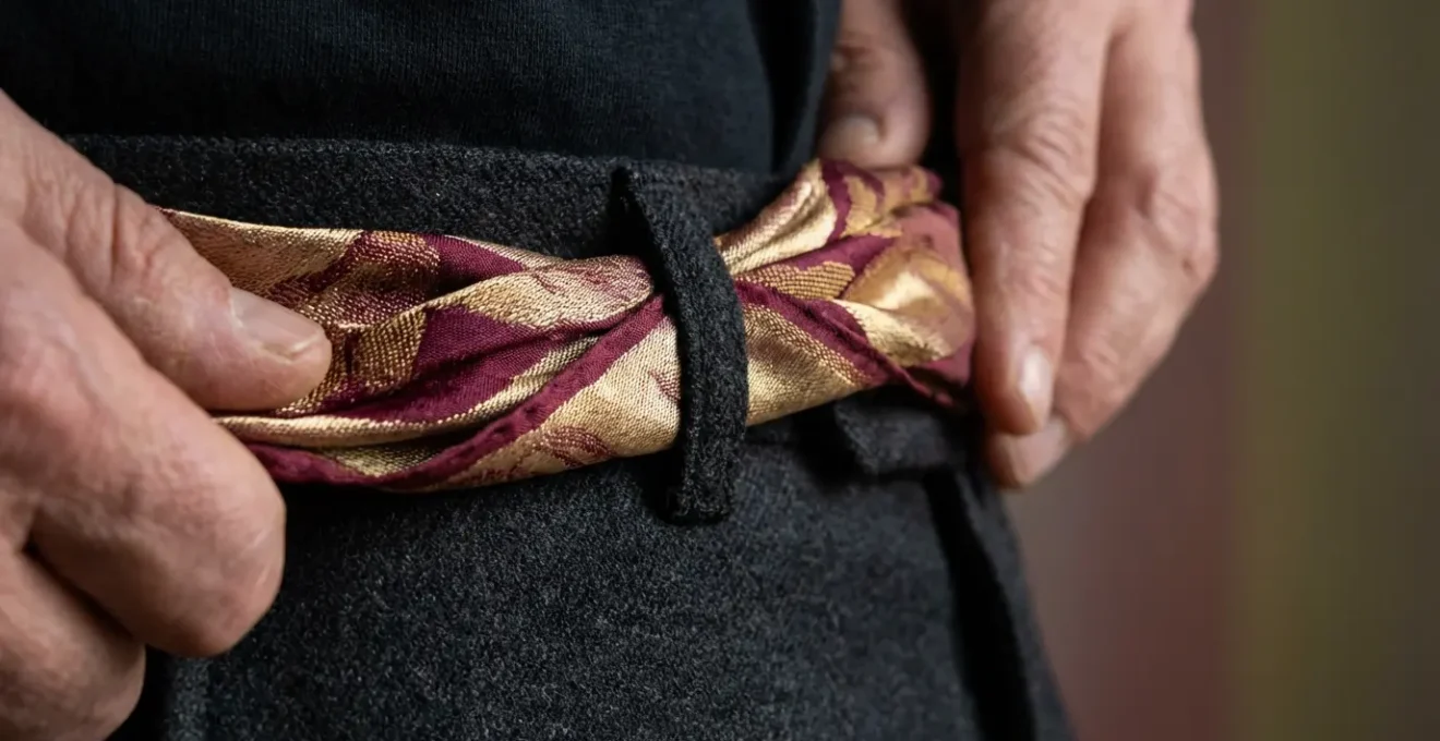 Gros plan sur une ceinture nouée avec un carré de soie fixé aux passants d'un pantalon